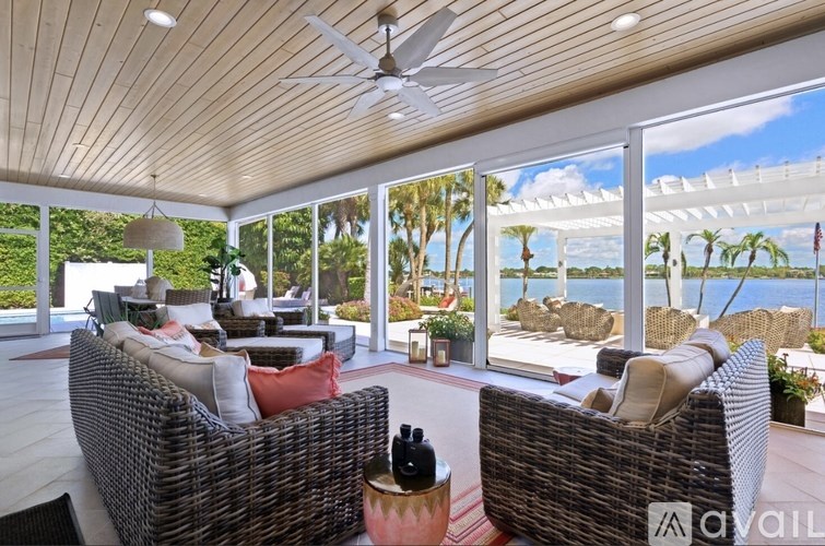 A patio with a wicker sofa and a table with a bottle on it.