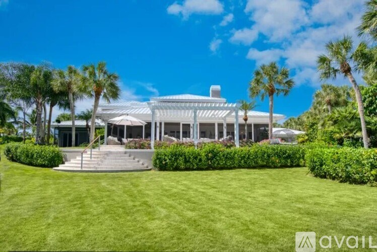 A large white house with a glass roof and a green lawn in front.