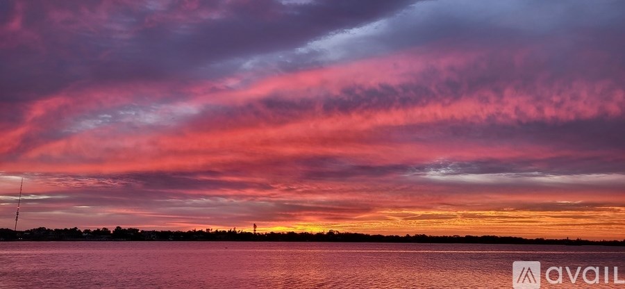 A beautiful sunset over the water with a pink and purple sky.