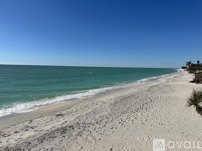 A beach with white sand and a clear blue sky.