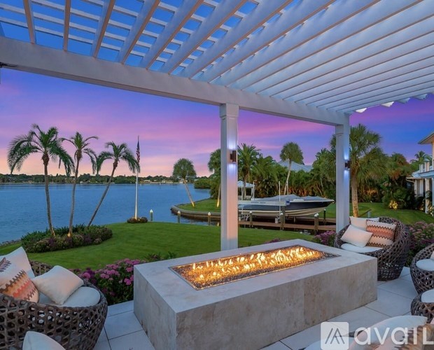 A patio with a fire pit and chairs overlooking a body of water.