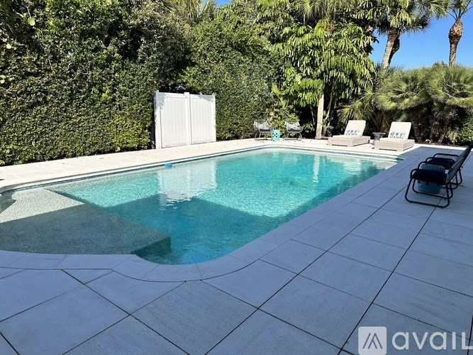 A pool surrounded by trees and a white fence.