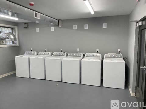 A row of white washing machines are lined up in a laundromat.