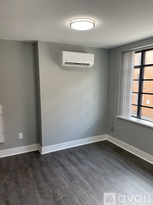 A room with a window and a wall-mounted air conditioner.