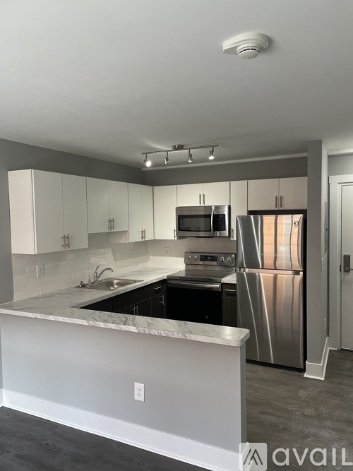 A modern kitchen with stainless steel appliances and a marble countertop.