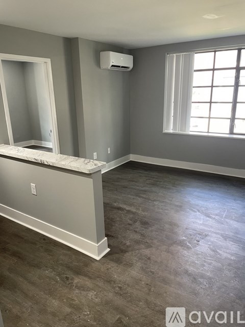 A room with a window, a mirror, and a marble countertop.