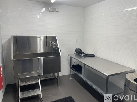 A clean, empty kitchen with stainless steel appliances and white tiled walls.