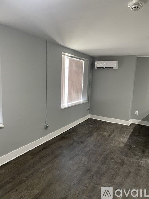 A room with a window and a wall-mounted air conditioner unit.