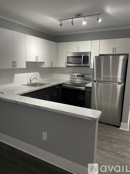 A modern kitchen with a stainless steel refrigerator and a marble countertop.