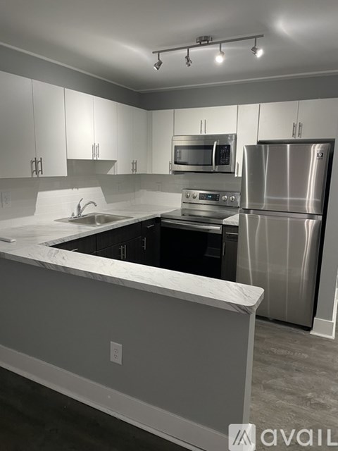 A modern kitchen with a stainless steel refrigerator and a marble countertop.