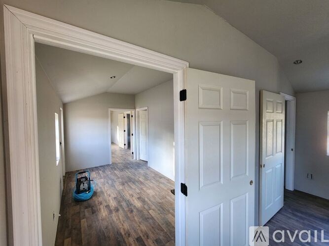 A room with a white door and a blue toy car on the floor.