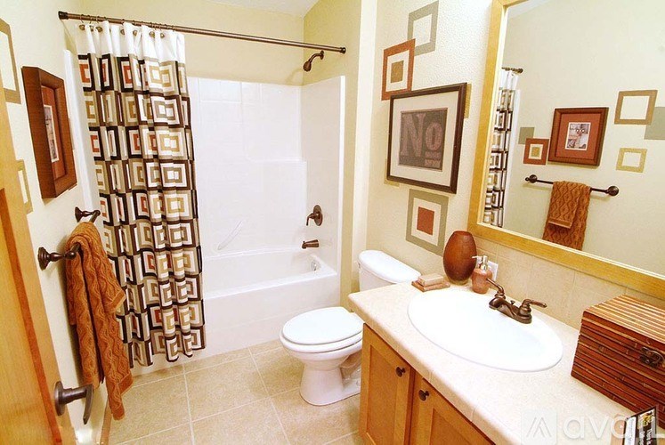 A bathroom with a white toilet, a white sink, and a shower curtain with a brown pattern.