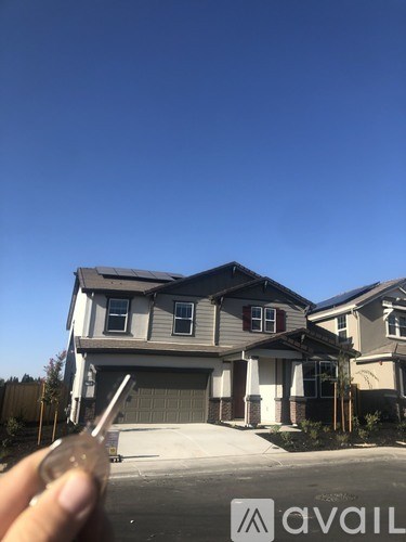 A person is holding a key in front of a house with the logo "avaiL" on it.