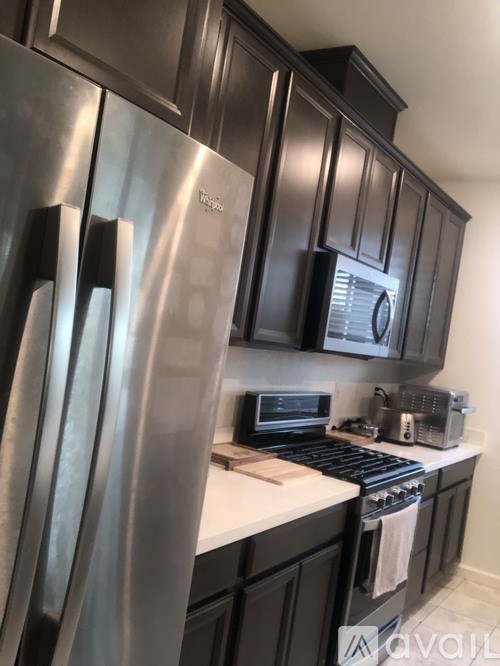 A kitchen with a stainless steel refrigerator and black cabinets.