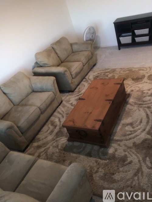 A brown coffee table in the middle of a room with a grey sofa and a white wall.