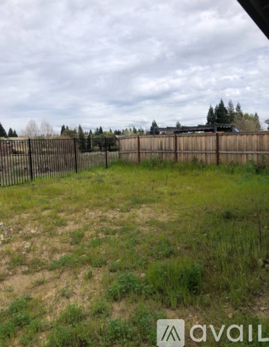 A grassy field with a fence and trees in the distance.
