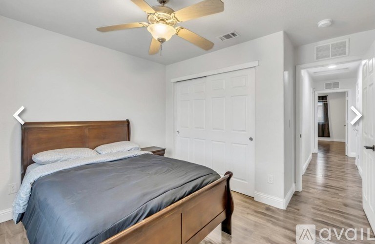 A bedroom with a bed, a ceiling fan, and a door.