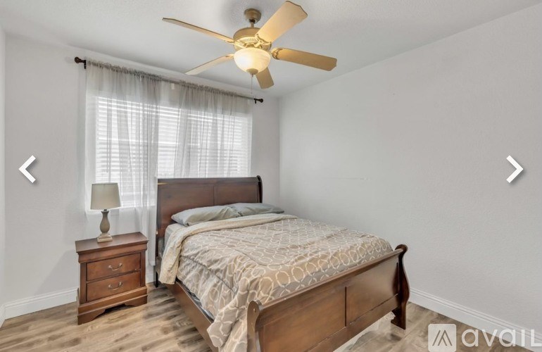 A bedroom with a bed, nightstand, and a ceiling fan.