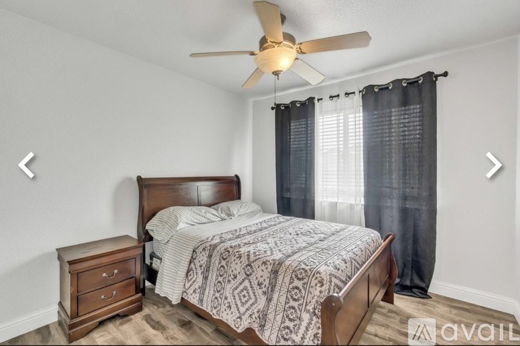A bedroom with a bed, nightstand, and a ceiling fan.