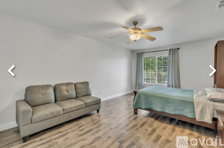 A bedroom with a bed, a couch, and a ceiling fan.