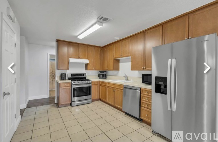 A kitchen with wooden cabinets and stainless steel appliances is available for rent.
