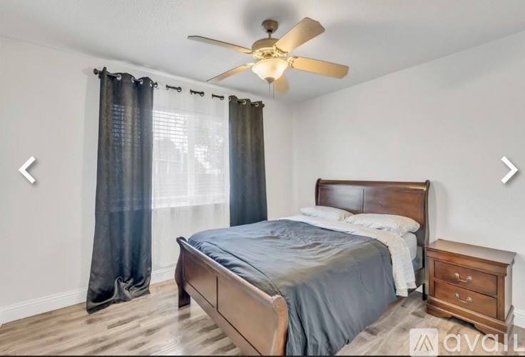 A bedroom with a bed, nightstand, and ceiling fan.