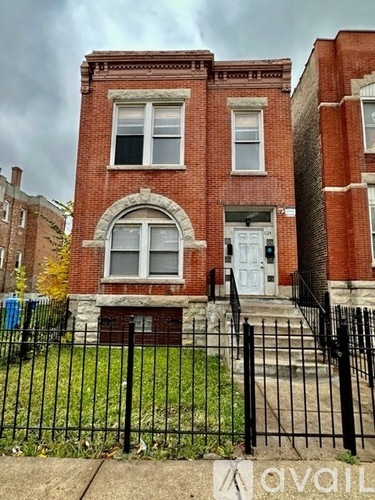 A red brick building with a white door and a black fence in front.