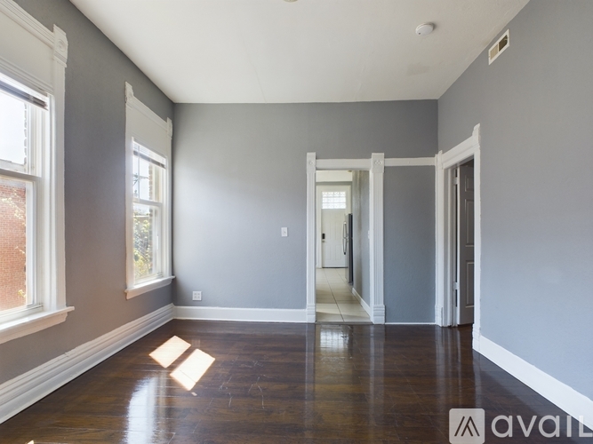A spacious room with wooden floors and white trimmed windows.