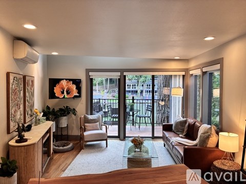 A living room with a couch, chair, and a table with a vase of flowers on it.