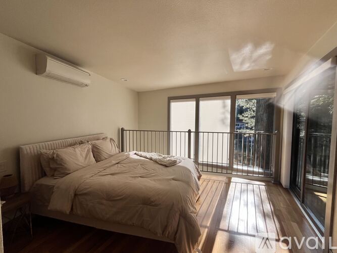 A bedroom with a large bed and sliding glass doors leading to a balcony.