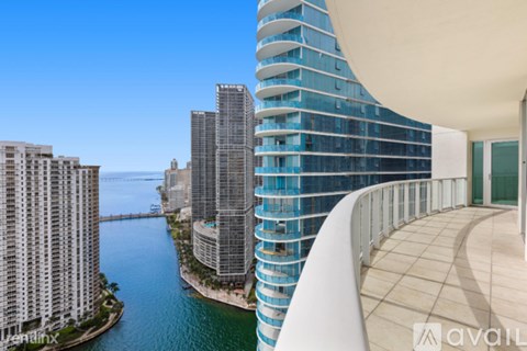 A modern building with a curved balcony overlooking a body of water.