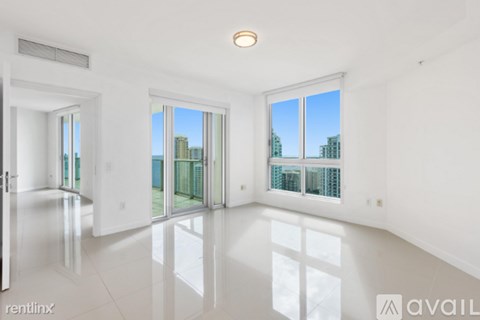 A spacious, empty room with a view of the cityscape outside the windows.