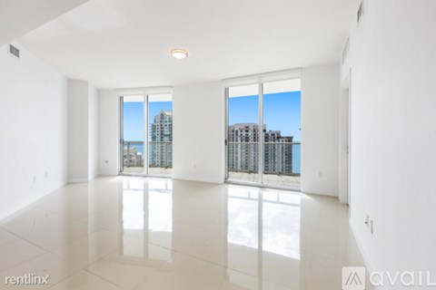 A spacious, empty room with a view of the city through large windows.