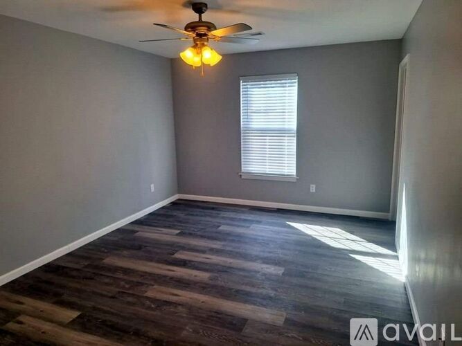 A room with a ceiling fan and wooden flooring.