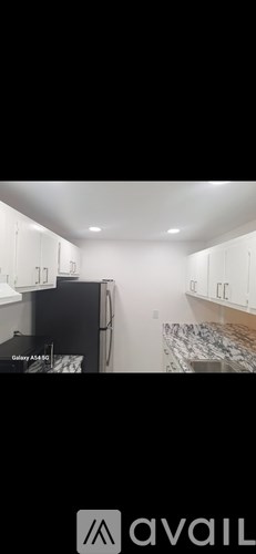 A kitchen with white cabinets and a black fridge.