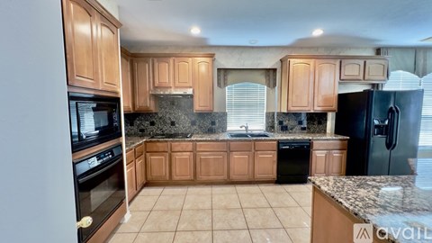 A kitchen with wooden cabinets and a granite countertop.