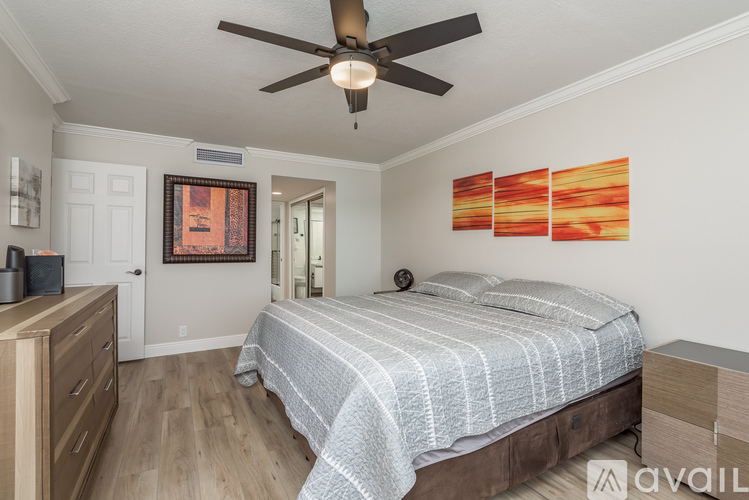 A bedroom with a bed, dresser, and ceiling fan.