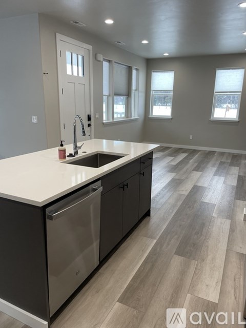 A modern kitchen with a stainless steel dishwasher and wooden flooring.