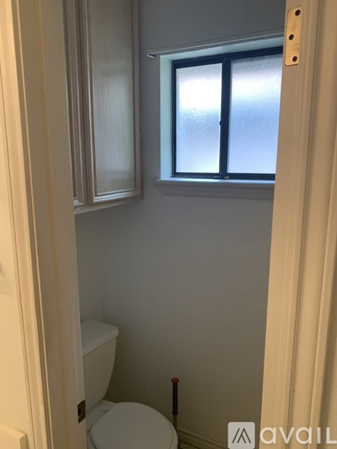 A bathroom with a toilet and a window.