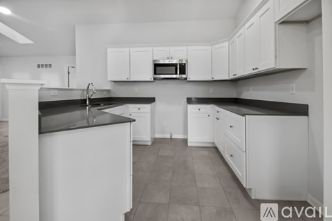 A kitchen with white cabinets and black countertops.