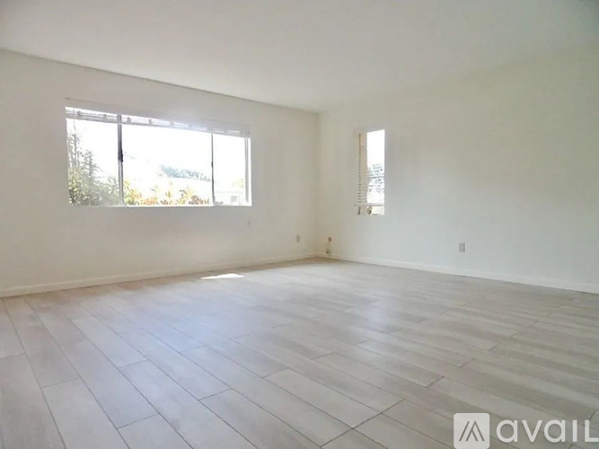 A spacious room with a large window and a tiled floor.