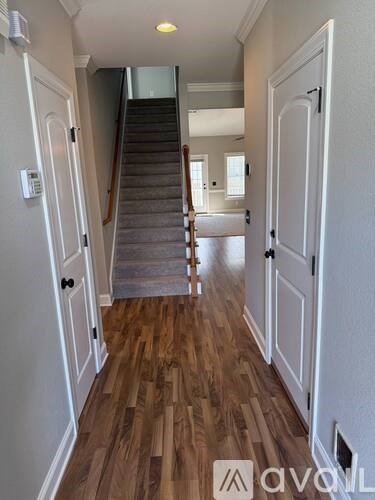 A hallway with a staircase and wooden floors.
