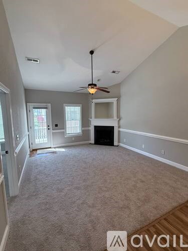 A spacious room with a ceiling fan and a fireplace.