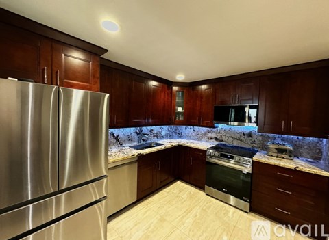 A kitchen with wooden cabinets and a stainless steel refrigerator.