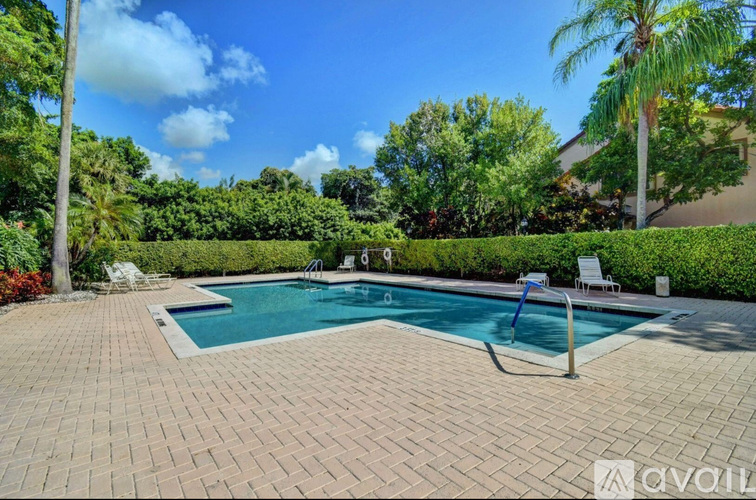 A pool surrounded by a brick patio and palm trees.