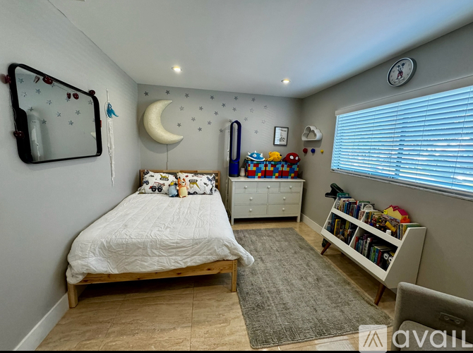 A child's bedroom with a bed, dresser, and a window with blinds.