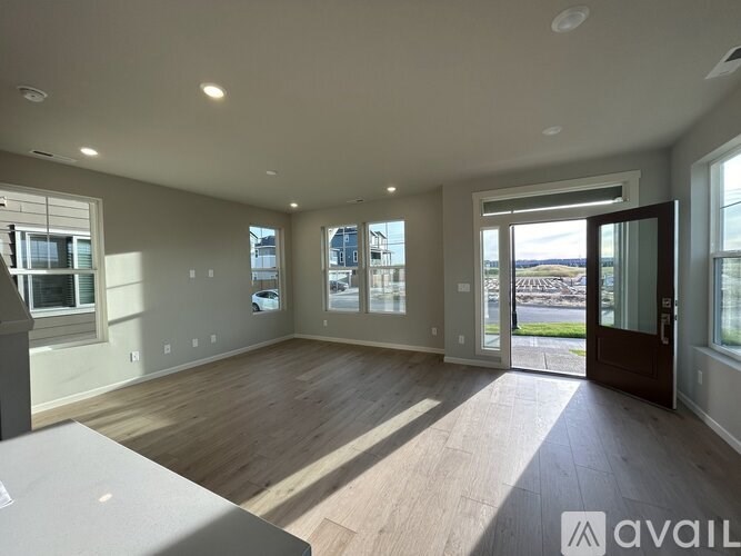A spacious room with wooden floors and large windows.