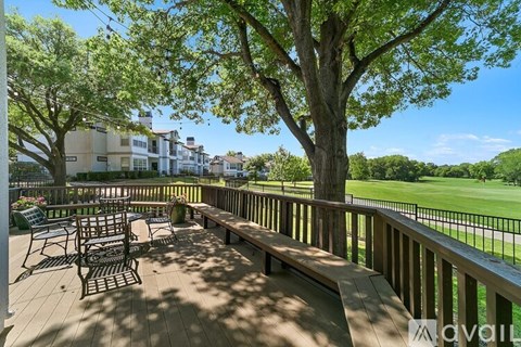 A deck with a table and chairs overlooking a green field.