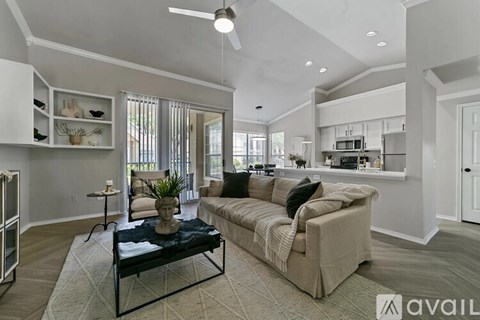 A living room with a couch, a coffee table, and a ceiling fan.