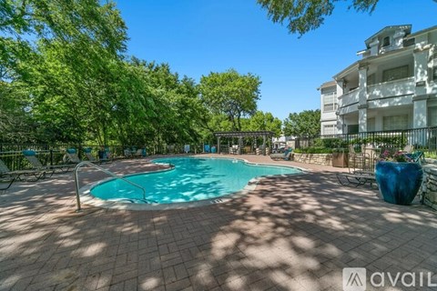 A pool surrounded by trees and a building in the background.